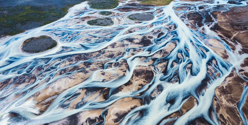 Aerial shot of a braided river, meandering around raised rocks.