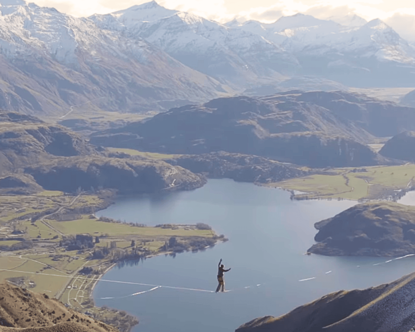A man highlining over a lake and mountains in New Zealand
