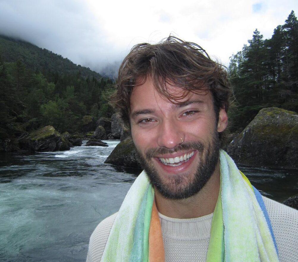 Justin, cofounder of Indigo Media Solutions, smiling at the camera with a mountainscape in the background